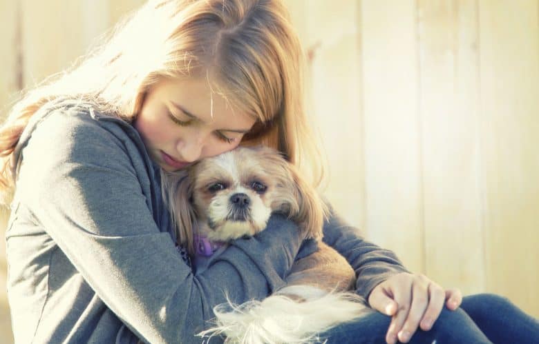 A teenage girl hugging tight her dog