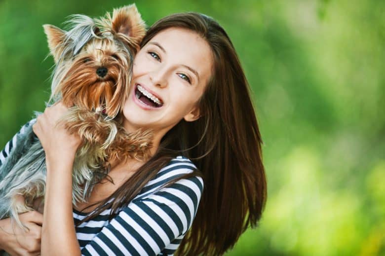 Beautiful young lady carrying her little dog