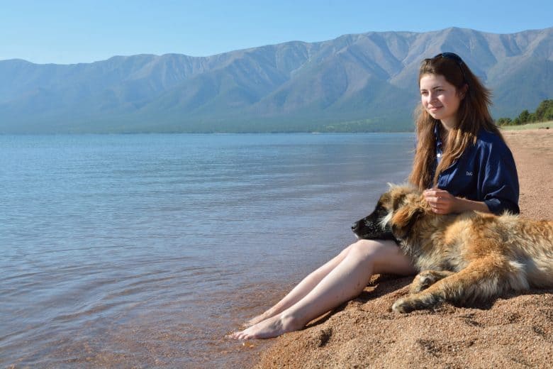 A Leonberger resting with a woman on a lake