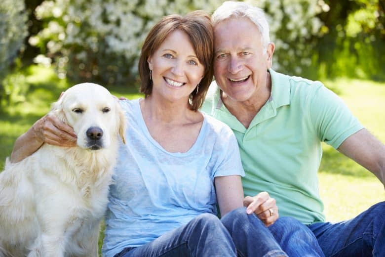 happy senior couple sitting with their Labrador Retriever