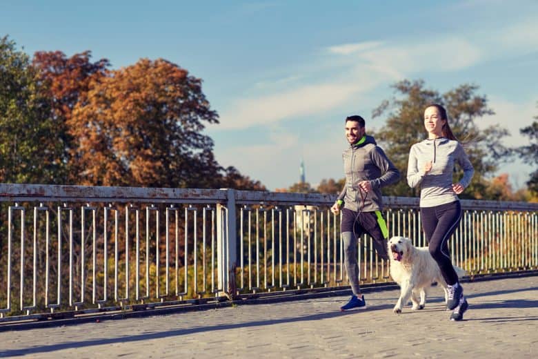 A man and a woman running with their dog