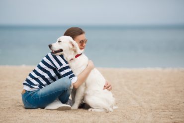 A woman hugs a white Golden Retriever dog