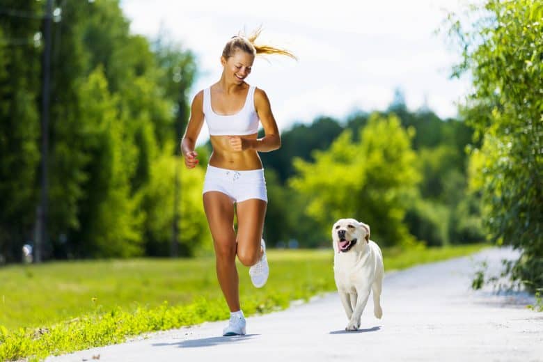 A woman running with a Labrador Retriever