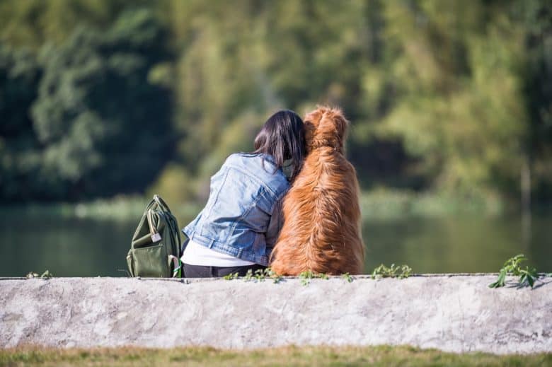 A woman sitting close to a red Golden Retriever dog