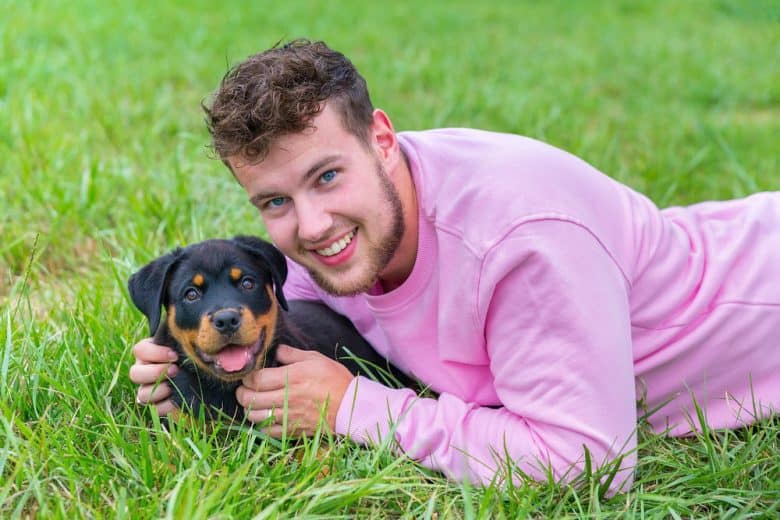 Dog owner holds lovingly Rottweiler puppy