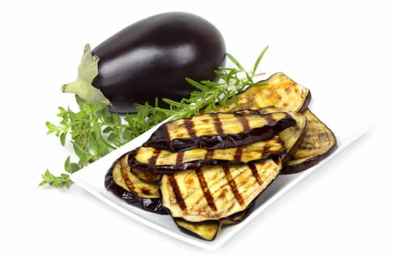A whole, fresh eggplant and grilled eggplant slices